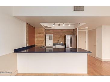 Modern kitchen features an island with blue countertops, stainless steel refrigerator, and stylish lighting at 4750 N Central Ave # N7, Phoenix, AZ 85012
