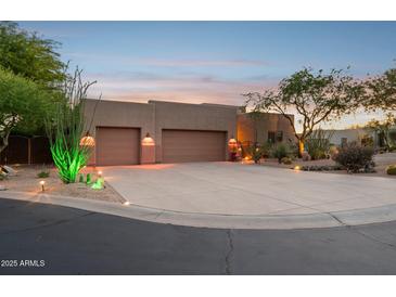 Desert home exterior with a wide driveway, two-car garage, desert landscaping and exterior lighting at 11299 E Greythorn Dr, Scottsdale, AZ 85262