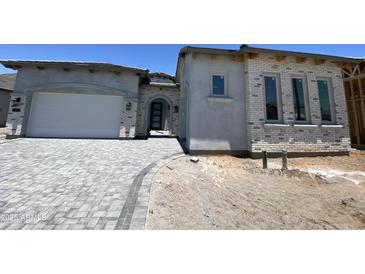 Modern exterior showcasing a brick facade, gray driveway, and an arched doorway entrance at 1160 E Peach Tree Dr, Chandler, AZ 85249