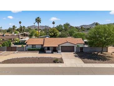 Charming single-story home with a well-maintained front yard, mountain views, and an attached two-car garage at 5101 E Paradise Dr, Scottsdale, AZ 85254