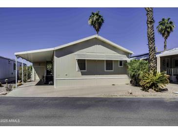 Charming home exterior with covered parking, trimmed green shrubs, and desert landscaping under a clear blue sky at 17200 W Bell Rd # 1602, Surprise, AZ 85374