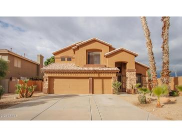 Inviting home with a three-car garage, neutral stucco and stacked stone accents at 760 N Swallow Ln, Gilbert, AZ 85234