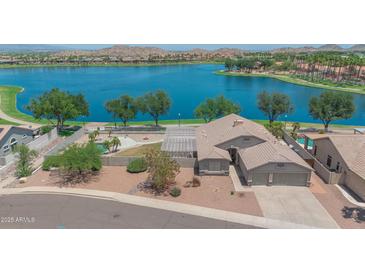 Beautiful lakefront home featuring a backyard pool and a covered patio, perfect for outdoor entertaining at 18088 W San Alejandro Dr, Goodyear, AZ 85338