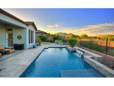 Resort-style pool with a tranquil waterfall feature and mountain views, perfect for relaxation and outdoor enjoyment at 40613 N Candlewyck Ln, Anthem, AZ 85086