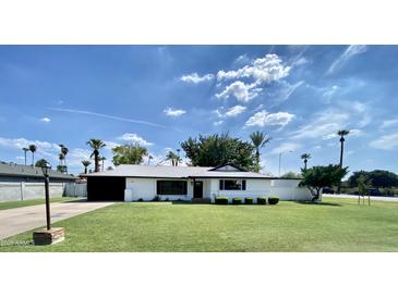Charming single-story home featuring a lush green lawn, beautiful blue skies, and mature palm trees at 541 W Marlette Ave, Phoenix, AZ 85013