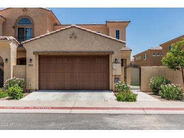 Tan home featuring a two-car garage, pedestrian gate and colorful flowers at 1367 S Country Club Dr # 1331, Mesa, AZ 85210