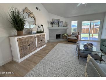 Inviting living room featuring a decorative fireplace, stylish console and sliding glass doors to the backyard at 4608 W Gail Dr, Chandler, AZ 85226