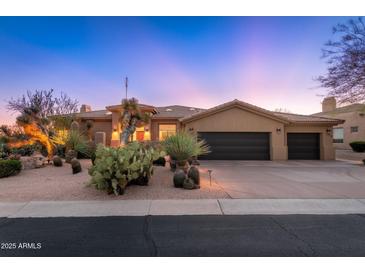 Southwestern home with desert landscaping, a three car garage, and a sunset backdrop at 28768 N 95Th Way, Scottsdale, AZ 85262