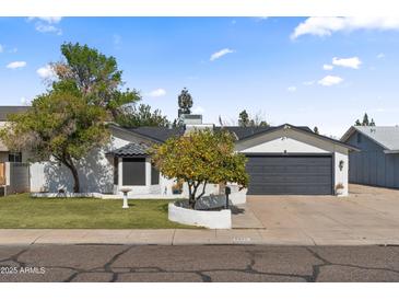 Charming single-story home with mature landscaping and a gray two-car garage door at 6550 W Wolf St, Phoenix, AZ 85033