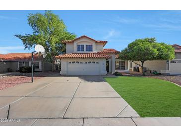 Charming two-story home featuring a red tile roof, spacious driveway with basketball hoop, and well-maintained landscaping at 7658 W Boca Raton Rd, Peoria, AZ 85381
