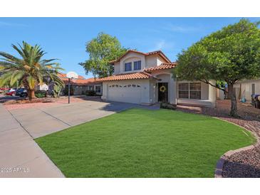 Charming two-story home boasting a red tile roof, well-manicured lawn, and desert landscaping with a palm tree at 7658 W Boca Raton Rd, Peoria, AZ 85381