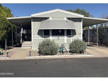 Charming mobile home featuring carport, awning, and well-maintained landscaping at 300 S Val Vista Dr # 54, Mesa, AZ 85204