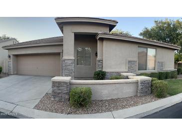 Inviting single-story home featuring stone accents, a two car garage, and desert landscaping at 7052 E Kessler Ave, Mesa, AZ 85209