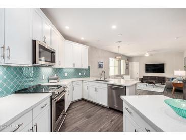 Bright kitchen with stainless appliances, white cabinets, granite countertops, and decorative tile backsplash at 2511 W Queen Creek Rd # 258, Chandler, AZ 85248