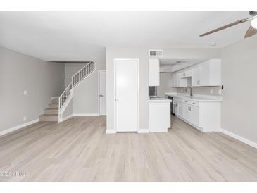 Open-concept living room features wood floors and seamlessly integrates the kitchen with white cabinets at 286 W Palomino Dr # 147, Chandler, AZ 85225