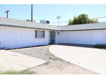 Cozy house with a gray roof, a gated front door, a garage, and a spacious driveway at 3651 W Mariposa St, Phoenix, AZ 85019