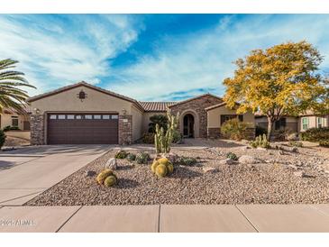 Charming home features a desert landscape, stone accents, and a brown two-car garage at 15452 W Skyview Way, Surprise, AZ 85374