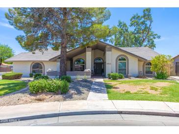 Charming single-story home featuring arched windows and a well-maintained lawn and lovely desert landscaping at 3611 E Dartmouth Cir, Mesa, AZ 85205