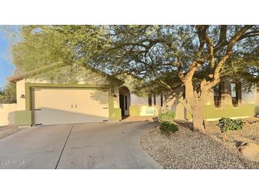 Charming home featuring a two-car garage, desert landscaping, and a mature tree at 7313 S 25Th S Dr, Phoenix, AZ 85041