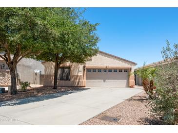 Lovely home featuring a well-kept lawn, mature trees, and a two-car garage, creating an inviting curb appeal at 874 E Lamonte St, San Tan Valley, AZ 85140