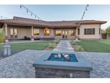 Stunning backyard featuring lush lawn, desert landscaping, and cozy fire pit area at 9183 W Shamel Ash Rd, Peoria, AZ 85383