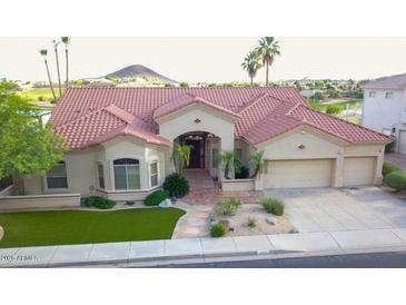 Beautiful single-story home on the golf course featuring lush desert landscaping and mature palm trees at 2053 E Clubhouse Dr, Phoenix, AZ 85048