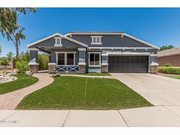 Charming home boasts manicured lawn, stone accents, and attached two car garage at 2542 E Los Alamos St, Gilbert, AZ 85295