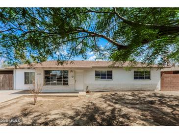Charming single-story home featuring a brick facade, complemented by mature trees and a well-maintained lawn at 3238 W Rose Ln, Phoenix, AZ 85017
