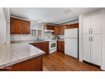 Charming kitchen featuring brown wooden cabinets, granite countertops, and essential modern white appliances at 9431 E Coralbell Ave # 192, Mesa, AZ 85208