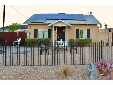 Charming bungalow-style home featuring solar panels, a cozy porch, and a wrought-iron fence at 2014 N 17Th Pl, Phoenix, AZ 85006