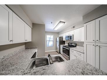 Modern kitchen with stainless steel appliances, white cabinets, and stylish granite countertops at 2025 E Campbell Ave # 137, Phoenix, AZ 85016