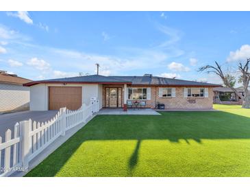 Charming single-story home featuring a well-maintained lawn, brick accents, and a classic white picket fence at 2234 N 74Th Way, Scottsdale, AZ 85257