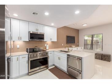 Modern kitchen featuring white cabinetry, stainless steel appliances, and a spacious quartz countertop at 3150 E Beardsley Rd # 1081, Phoenix, AZ 85050