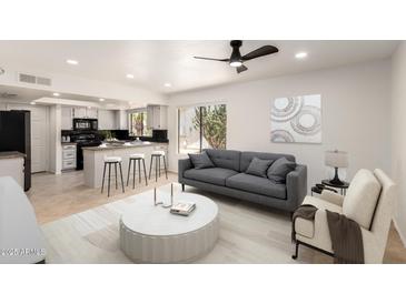 Bright living room with an open-concept kitchen and a modern gray sofa at 9645 W Kimberly Way, Peoria, AZ 85382