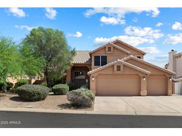 Charming two-story home featuring a three-car garage and a beautifully landscaped front yard at 12935 E Mercer Ln, Scottsdale, AZ 85259