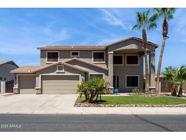 Two-story home featuring desert landscaping, a three-car garage, and a covered porch at 20226 N Madison Dr, Maricopa, AZ 85138