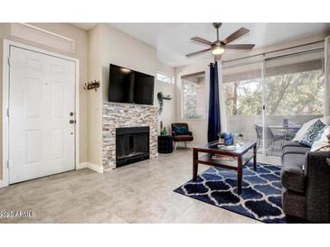 Inviting living room with stacked stone fireplace, modern fan, and sliding doors to the patio at 3830 E Lakewood E Pkwy # 3014, Phoenix, AZ 85048