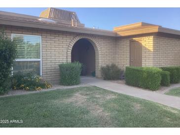 Charming brick home featuring an arched entryway and neatly manicured landscaping at 1036 E Wagon Wheel Dr, Phoenix, AZ 85020