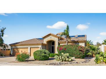Charming single-story home with desert landscaping, a three-car garage, and solar panels at 10897 S Turtle Dove S Dr, Goodyear, AZ 85338