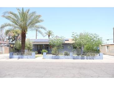 Charming single-story home featuring desert landscaping, a palm tree, and solar panels at 2718 W Montebello Ave, Phoenix, AZ 85017