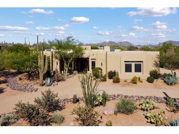 Beautiful tan home with mature landscaping, cactus, and mountain views in the background at 27203 N 64Th Way, Scottsdale, AZ 85266
