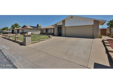 Charming single-level home featuring a well-manicured lawn and an expansive driveway at 5349 W Acapulco Ln, Glendale, AZ 85306
