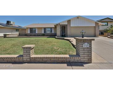 Inviting front yard with lush lawn, desert landscaping, and an elegant brick planter at 5349 W Acapulco Ln, Glendale, AZ 85306