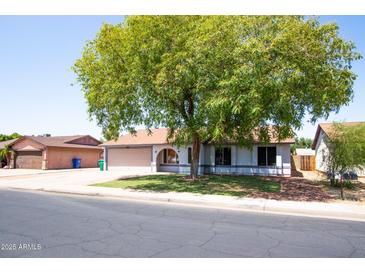 Charming single-story home featuring a large tree, well-maintained lawn, and inviting curb appeal at 2338 E Javelina Ave, Mesa, AZ 85204