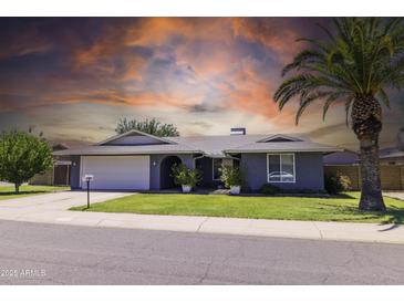 Charming single-story home with a well-manicured lawn and mature palm tree under an orange-hued sky at 5751 W Muriel Dr, Glendale, AZ 85308