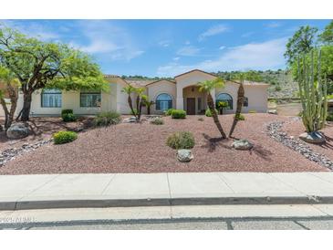Inviting single-story home featuring desert landscaping and palm trees in the front yard at 5949 W Pinnacle Hill Dr, Glendale, AZ 85310