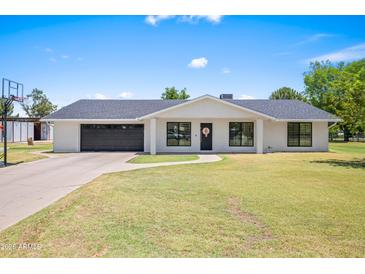 Charming single-story home featuring a lush green lawn and modern exterior finishes at 802 E Harwell Rd, Gilbert, AZ 85234
