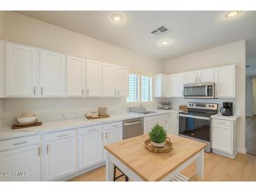 Bright kitchen with white cabinets, stainless steel appliances, and a wooden island at 125 N 22Nd Pl # 5, Mesa, AZ 85213