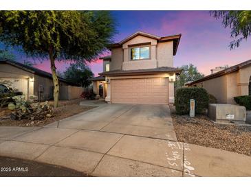 Charming two-story home featuring a neutral exterior, two-car garage, and mature desert landscaping at dusk at 21665 N 47Th Pl, Phoenix, AZ 85050