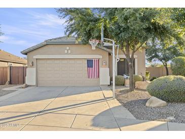 Charming single-story home featuring a two-car garage, beige exterior, and mature landscaping with a basketball hoop at 4111 S Dewdrop Ct, Gilbert, AZ 85297